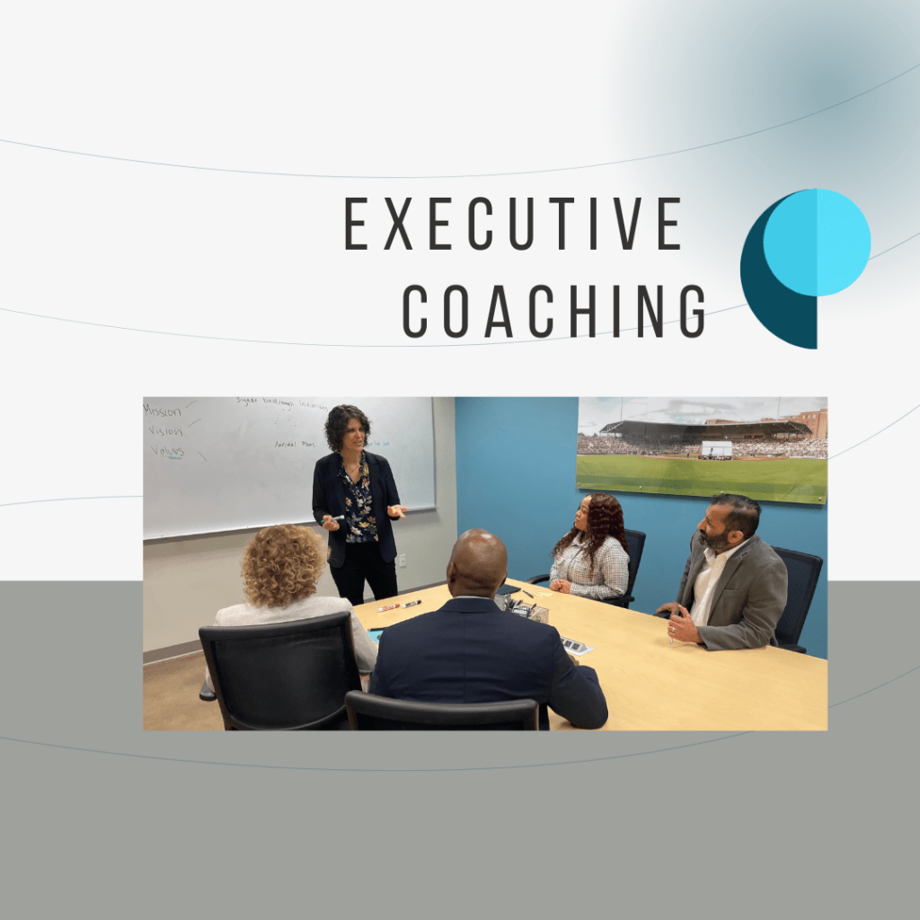 A business meeting focused on executive coaching, featuring a woman presenting to a group of diverse professionals at a conference table with a whiteboard in the background.